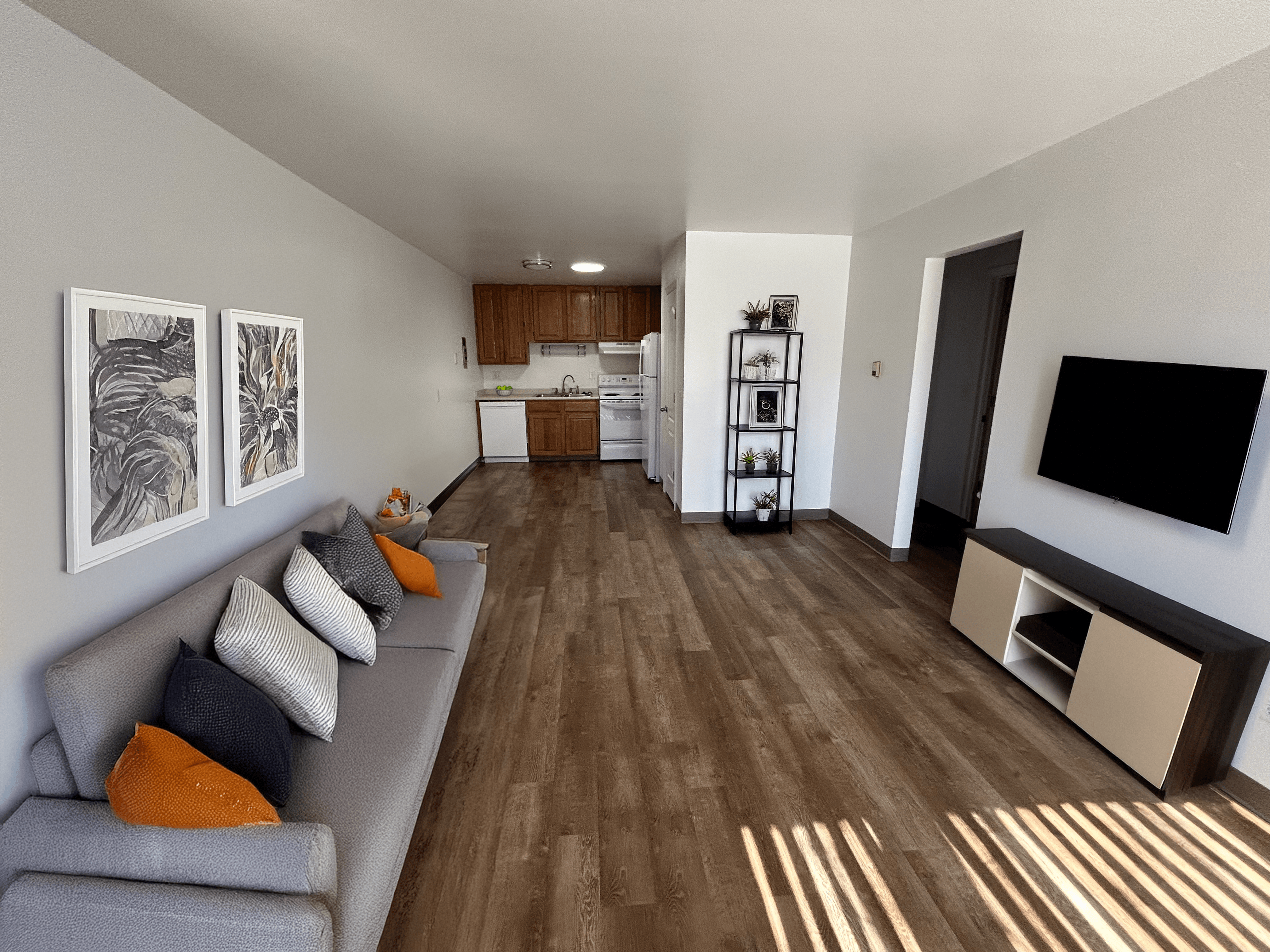 A living room with a grey couch and a wooden floor.